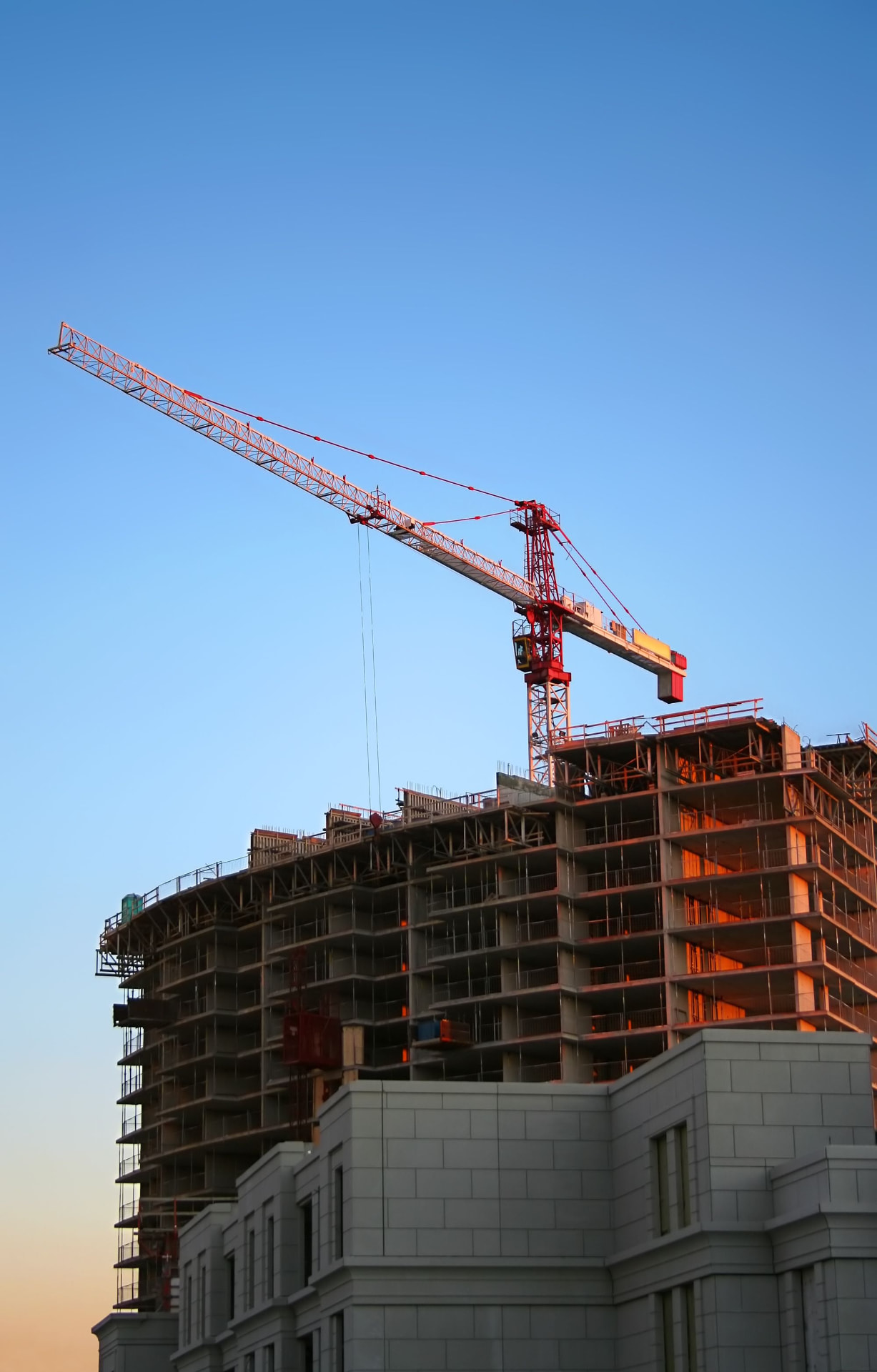 Edifício em construção com grua sob céu azul